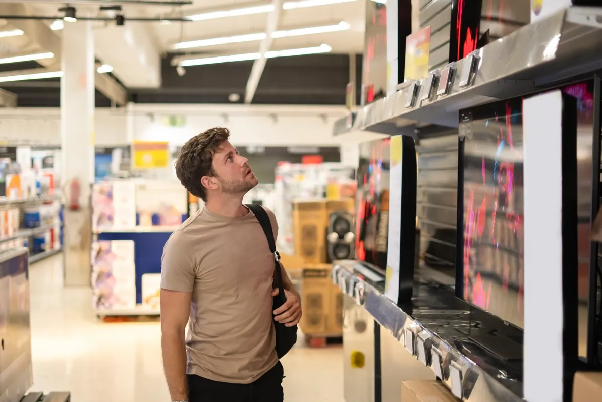 Un client comparant des téléviseurs dans un magasin d’électronique