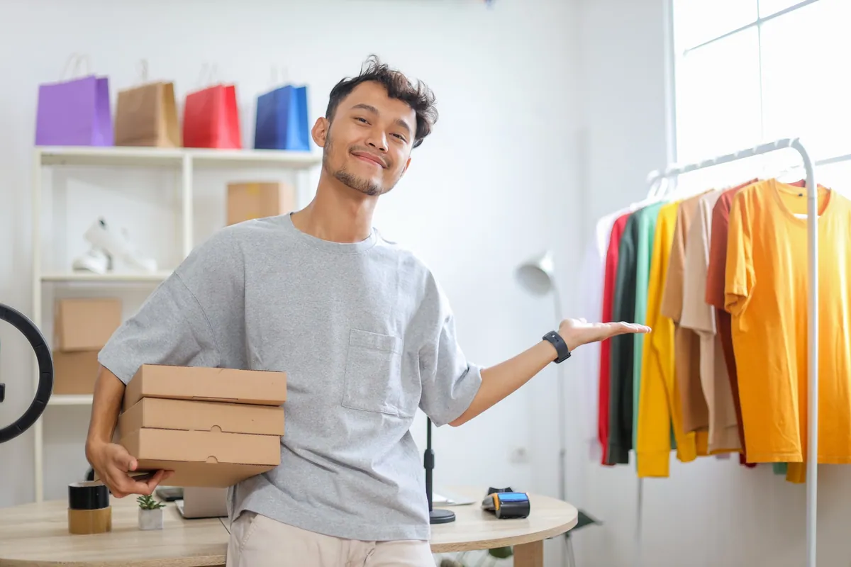 Un entrepreneur tenant des colis près de produits prêts à vendre