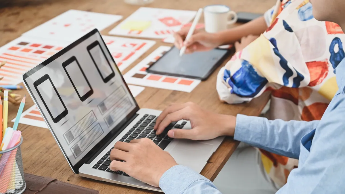 Des designers préparant des mises en page sur un ordinateur et une tablette